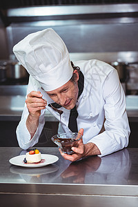 厨师在甜点上加巧克力酱汁厨师长职业男人厨房黑板厨艺推介会板块制服餐厅背景图片
