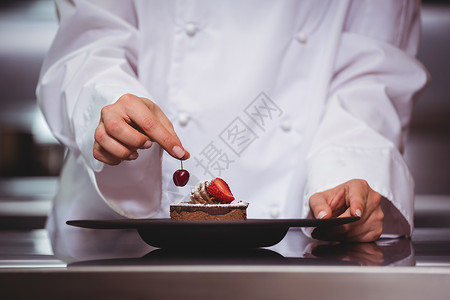 厨师把樱桃放在甜点上板块餐厅大楼厨艺女士食物厨师长准备女性酒店背景图片