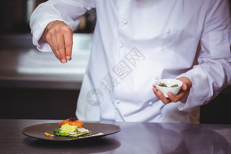 主厨在菜盘上喷洒香料男性准备厨师推介会制服男人推杆餐厅板块食物背景图片