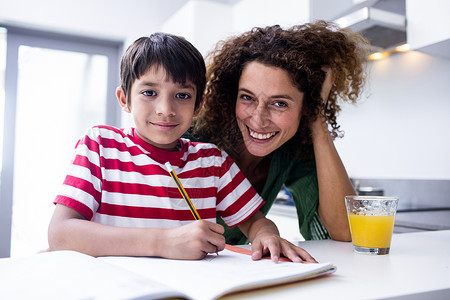 快乐的母亲帮助儿子做家庭作业背景图片