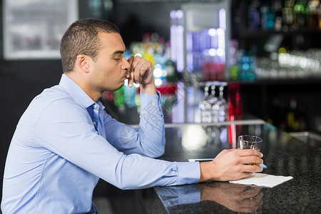 坐着喝酒的男人担心的商务人士喝酒喝威士忌背景