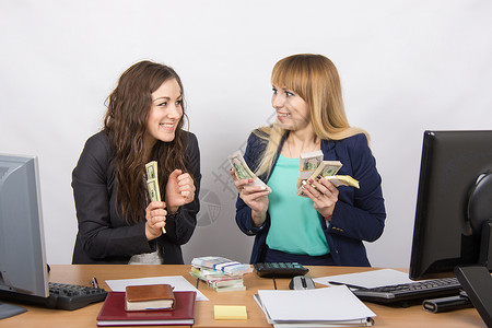 奖金分红素材两个非常快乐的办公室女孩 幸福地握着一大笔钱在手中背景
