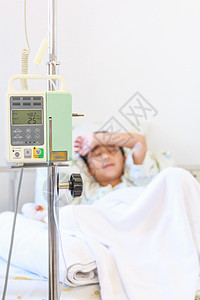 亚洲男孩睡在带输注泵静脉注射IV的病床上高清图片