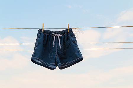 蓝色小短裤在天空背景下挂在衣绳上的短裤背景