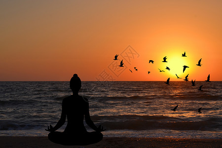 飞瑜伽日出时在海滩的瑜伽姿势中冥想的女人日落女性活力天空鸟类女孩太阳训练海洋身体背景