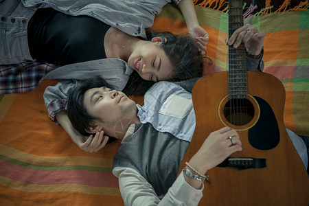 亚裔年轻男女的情侣 放轻松弹吉他背景图片