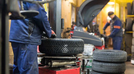 整体与部分在汽车修理服务中 专业汽车机械师更换轮车轮胎工作工人橡皮店铺涂层机器代品作坊男人车库背景