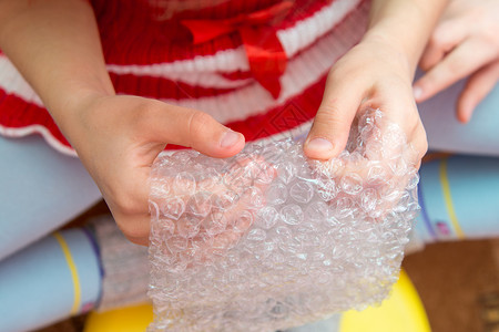 儿童双手的顶端视图 按下包装胶片上的泡泡高清图片