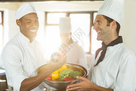 两个微笑的厨师 拿着一碗蔬菜快乐男人女性同事男性服务职业工人工作黑色背景图片
