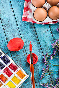 红色油漆鸡蛋用于彩色和油漆刷的鸡蛋画笔餐巾刷子蓝色假期视图紫色彩蛋桌子花朵背景