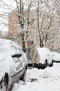 独立女性在冬天铲雪 在冬天风暴天气冻结城市雪堆暴风雪降雪停车位气候薄片背景图片