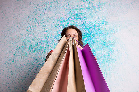开心的笑着女人在购物时展示彩色纸袋背景图片