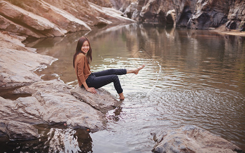在河岸上玩水的年轻女子双臂微笑自由喷涂裙子活动部位幸福阳光人体背景图片