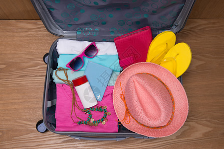 行李打开旅行和休假概念 开放旅行者带衣物的包袋钱包信用护照游客卡片桌子衣服电话相机配件背景
