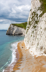 英国海年长夫妇在Eng的Dorset和高悬崖上走下海滩活动自由边缘岩石假期团队蓝色旅游冒险海岸背景