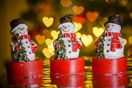 三个圣诞雪人和心形灯背景庆典魔法薄片季节玻璃气泡装饰品季节性假期背景图片