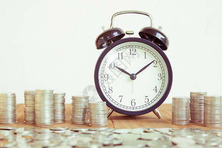 每小时费用一堆带有黑色闹钟的硬币 用于显示规划货币财务和商业会计概念 时间是带有时钟和硬币的货币概念 赚钱的时间 复古色调经济财富支付价格背景