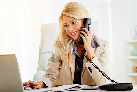 办公室的女商务人士打来电话上班族幸福水平经理电脑工作桌子秘书专业女性背景图片