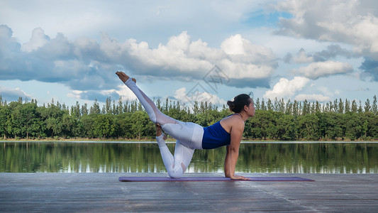 水平衡亚裔妇女练瑜伽姿势专注反射运动蓝色天空平衡身体公园女士地面背景