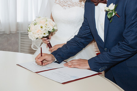 婚礼签名年轻夫妇在结婚文件上签名新娘已婚庆典办公室仪式协议传统丈夫婚姻家庭背景