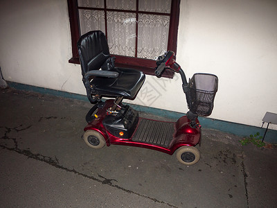 老年电动三轮在家庭残疾前停在门外的红色运动摩托车车背景