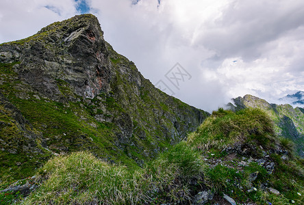 在草坡上方的岩石悬崖背景图片