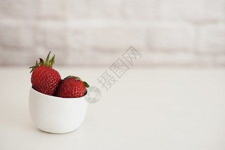 小白碗里新鲜的草莓 白色背景 砖墙 亮面料理背景图片