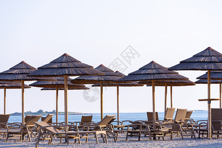 藤伞沙滩上的里德雨伞和甲板椅日光浴芦苇叶子海洋假期海岸线场景太阳热带椅子背景