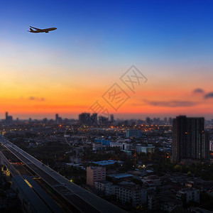 日出时在城市上空空中飞行的飞机休眠奢华速度假期商业航空航空公司建筑学翅膀客机空气背景