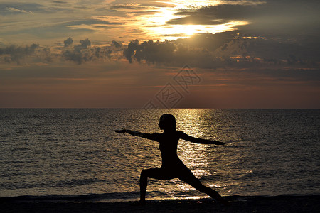 维拉巴德拉萨那妇女练瑜伽 日落时站在维拉巴德拉萨纳的姿势背景