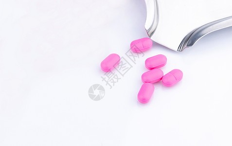 在不锈钢药物托盘附近的白色背景上的一堆粉红色药丸 诺氟沙星 400 mg 用于治疗膀胱炎 抗生素耐药性 抗菌药物使用要有合理的观背景图片