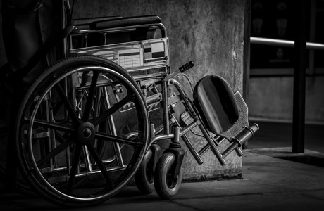 黑色萧条轮椅折叠在墙边 医院概念的悲伤消息 萧条与老龄化社会 孤独的空轮椅 服务病人和辅助残疾老人的医疗设备助手椅子车辆癌症诊所车轮黑与背景