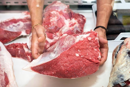 屠夫向顾客展示一块肉的肉男人市场工业店铺男性服务红色牛肉屠宰场动物背景图片
