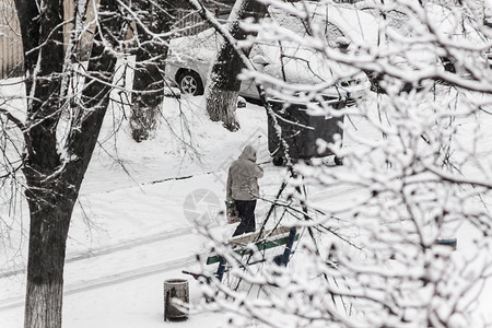 暴风雪一个路过者在大雪中穿过寒雪的市区院子气候男人薄片降雪假期场景血统女孩男性风暴背景