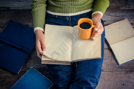 一撂书女人坐在木地板上 拿着咖啡杯看书饮料闲暇杯子成人咖啡房间食物白色教育知识背景