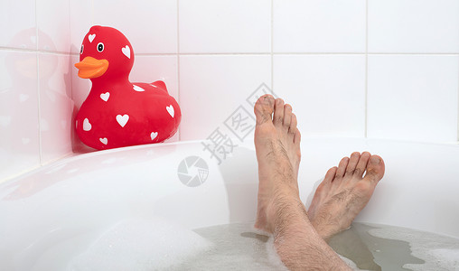 又有双下巴了鸭男人脚在浴缸里 有大块的橡皮鸭清洁泡沫男性漂浮浴室玩具童年肥皂乐趣塑料背景