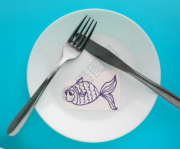 愚人节字素庆祝四月愚人节 一张配有叉子和刀的板块以及蓝底纸鱼背景