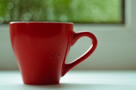 窗台边框白色窗台上的红咖啡杯 背景窗口和雨中 杯子位于边框左侧红色太阳窗户中心咖啡绿色背景
