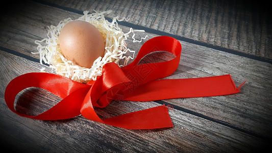 磁带模板素材木桌上稻草巢和红缎带中的鸡蛋风格海报礼物磁带乡村庆典假期干草金子木头背景