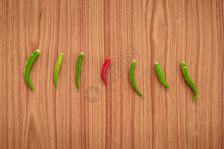 绿色清新线条效果元素一种红热辣的泰国辣椒或 Mirchi 在绿色辣椒中 在木质背景上水平排列 平躺 顶视图 从带有文本复制空间的人群概念中脱颖而出背景
