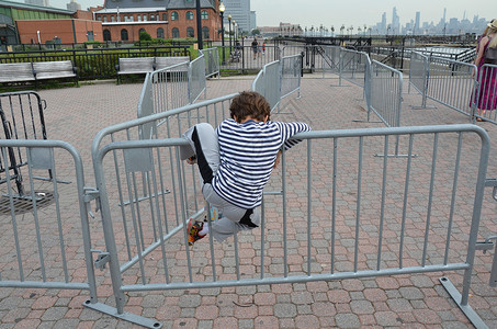 身穿黑白衬衫的男孩在纽约攀越铁栅栏背景
