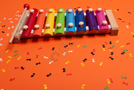 橙色铲子玩具彩虹色的木制木琴 供儿童使用 与橙色隔离 周围纸质五颜六色的音符意义童年创造力教育笔记游戏蓝色乐器木琴玩具背景