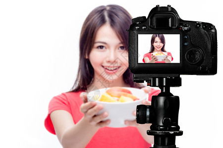 女孩拿着碗摄影机后面放着水果沙拉的亚洲食品花鼠摄影食物饮食女士拍照媒体内容美丽营养制作背景