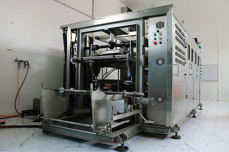 工厂内的真空热成型机 真空热成型机用于生产塑料包装 厂房内的真空热成型机 设备正面照片背景图片