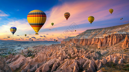内夫谢希尔热气球和红谷日落时在土耳其卡帕多西亚的戈雷梅冒险火鸡烟囱岩石洞穴石头日落自由航班天空背景