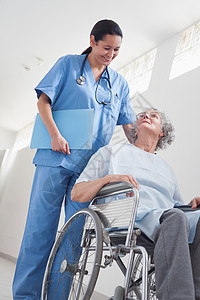 坐在护士旁边轮椅上的老年病人背景图片