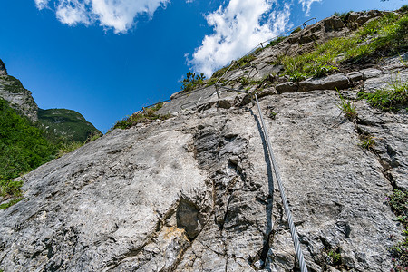 悬崖边的人奥地利瀑布边的Via ferrata登山者铁索顶峰首脑石灰石攀岩风险爱好岩石头盔背景