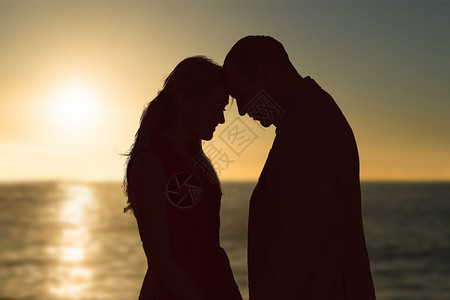 接吻日拥吻美日落日的复合图象日落男性情人感情快乐海洋海岸线长发亲密感短发背景