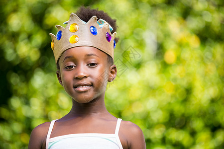 可爱王冠防尘塞一个混合种族女孩微笑并戴皇冠的肖像背景