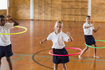 学生在学校体育馆玩hula hoop健身房快乐法庭闲暇乐趣班级纺纱男性游戏篮球背景图片